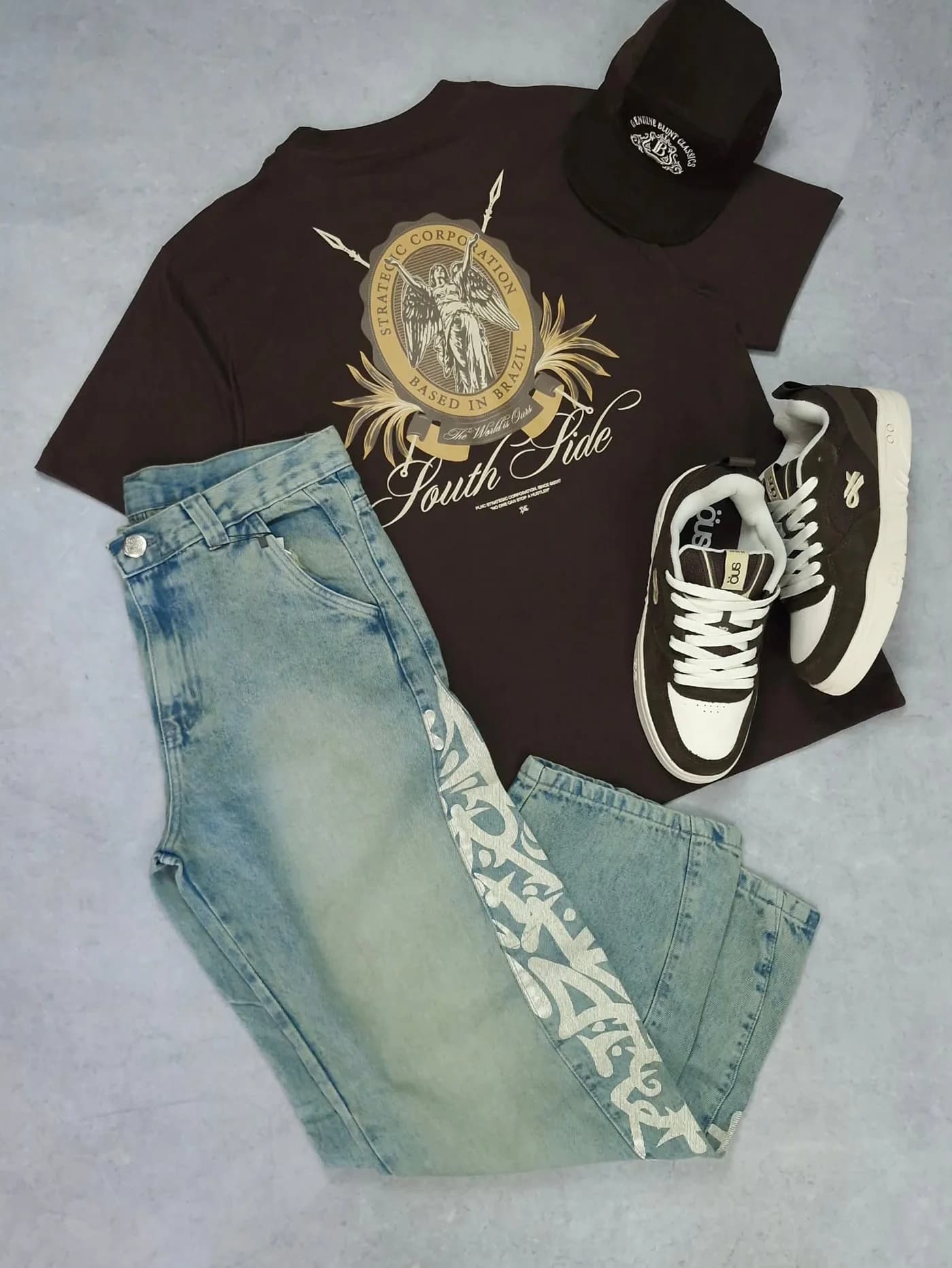 Kit no concreto: camiseta marrom com o emblema, calça jeans clara com lavagem dirty e tênis ÖUS marrom e branco